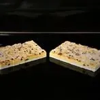 Zwei Dessertriegel auf dunklem Hintergrund, aufgeschnitten, um eine cremige Füllung und ein knuspriges Topping freizulegen.
