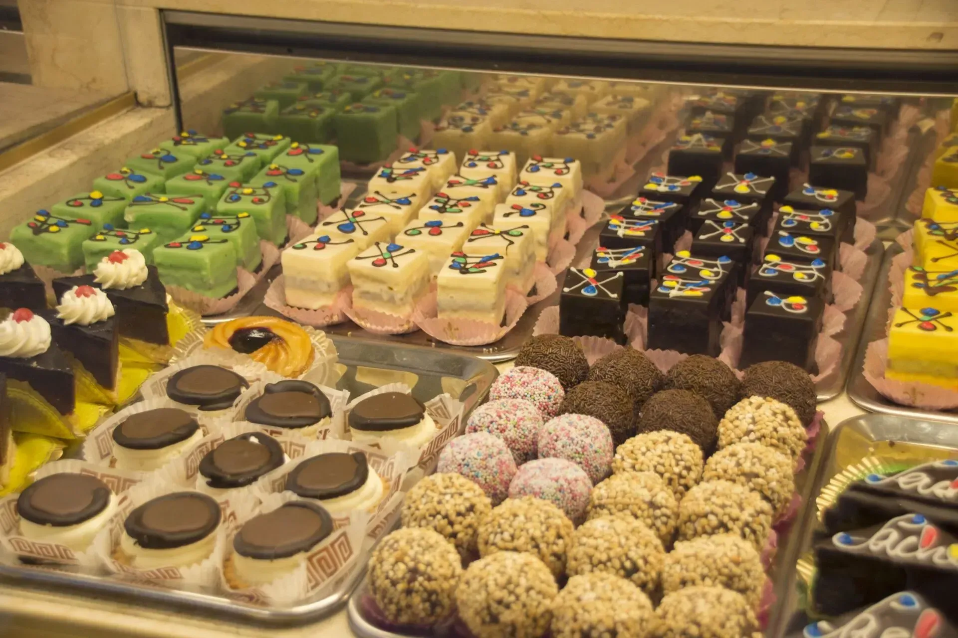 Verschiedene dekorierte Gebäckstücke und Pralinen in einer Bäckereivitrine ausgestellt