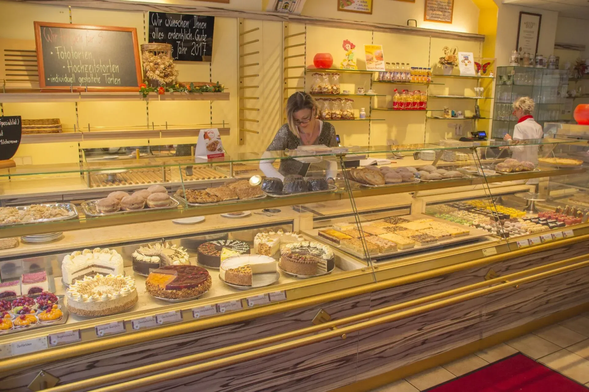 Auslage der Bäckerei mit verschiedenen Gebäcksorten und ein Verkäufer hinter der Theke