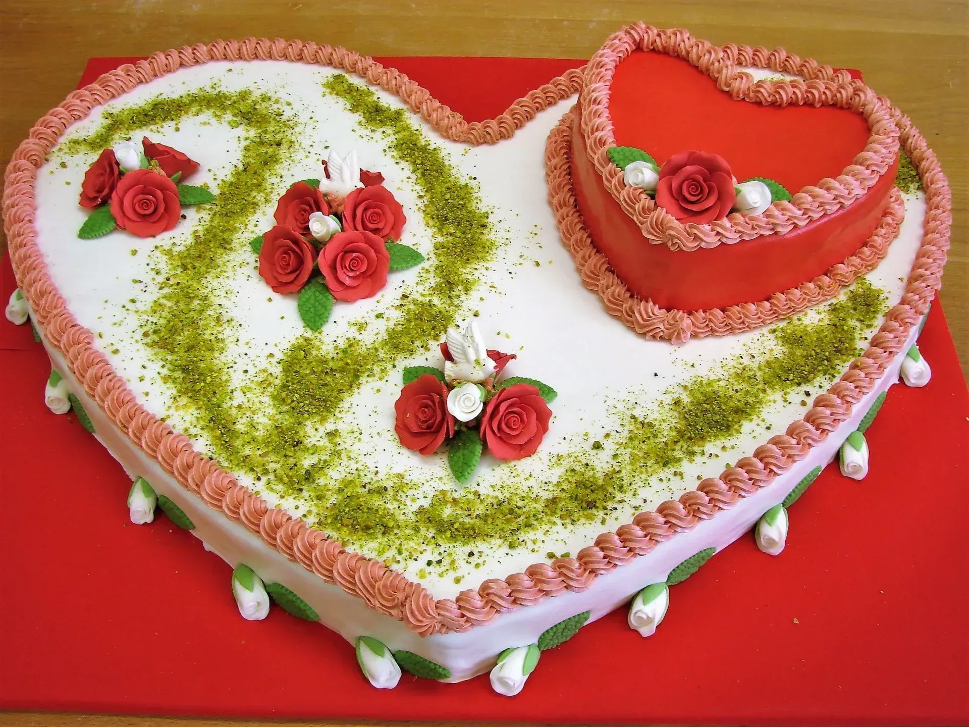 Herzförmiger, weiß-roter Kuchen mit Rosenverzierungen auf rotem Hintergrund