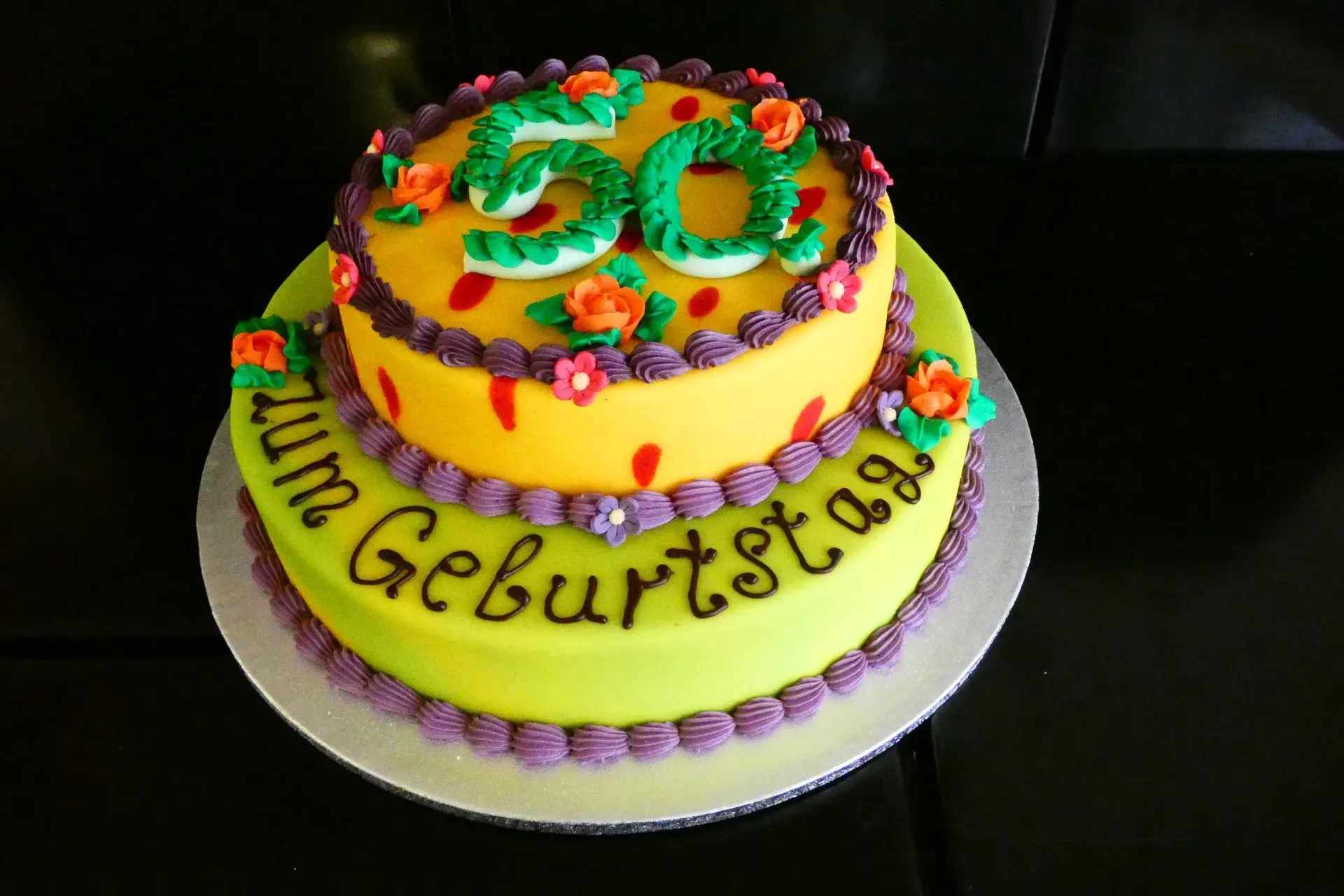 Bunte, zweistöckige Geburtstagstorte mit der Zahl „30“ als Tortenaufsatz und dem Schriftzug „Zum Geburtstag“ am unteren Rand