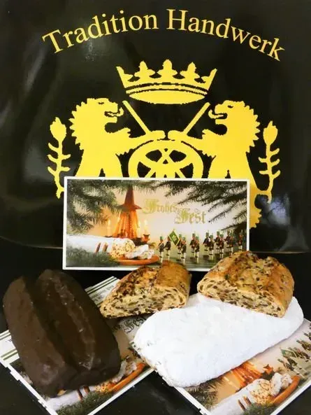 Auslage einer Bäckerei mit Broten und Gebäcksorten vor schwarz-goldenem Traditionsschild