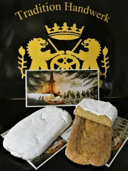 Zwei Puderzuckergebäcke vor einer schwarzen Tasche mit goldenem „Tradition Handwerk“-Wappen und einer Windmühlenszene