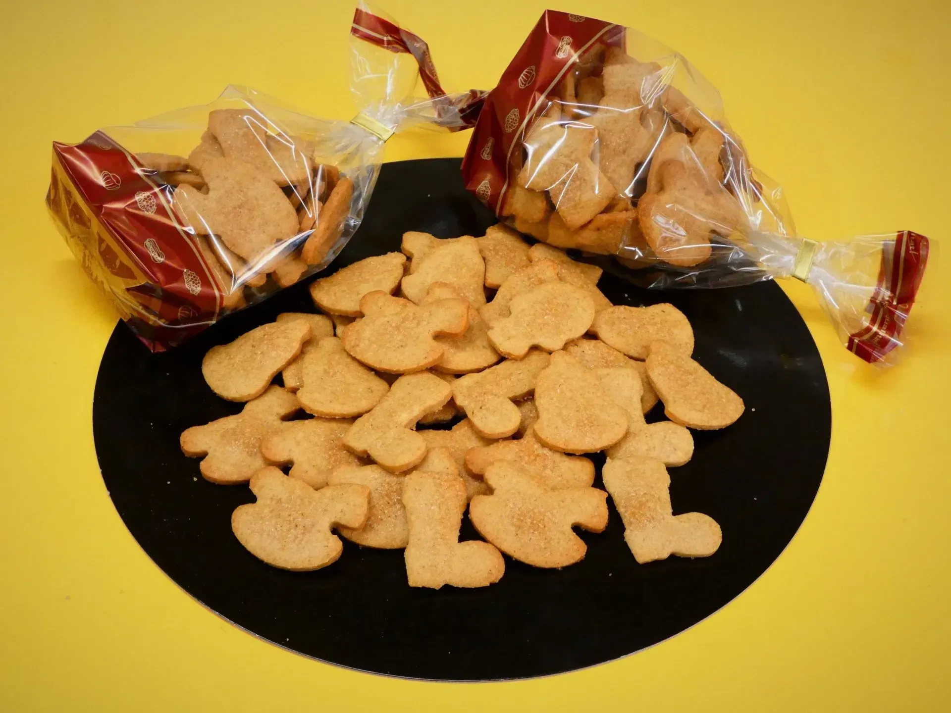 Verpackte und lose hellbraune Hundeleckerlis auf schwarzem Untergrund