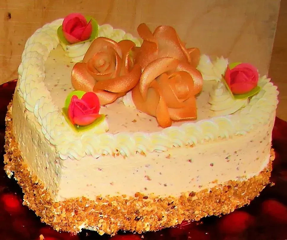 Herzförmiger Kuchen mit weißem Zuckerguss, pfirsichfarbenen Rosetten und rosa Rosenverzierungen.