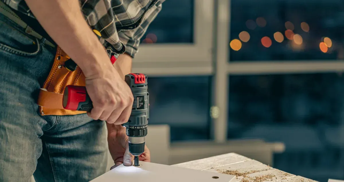 Persona utilizando un taladro para ensamblar muebles en el interior.