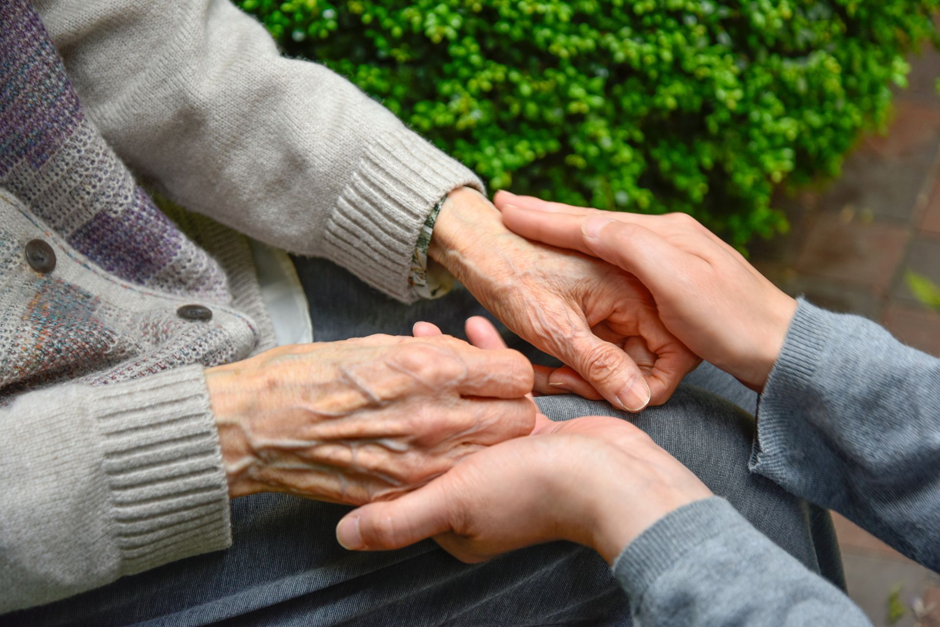 Eine Person hält die Hand einer älteren Frau.