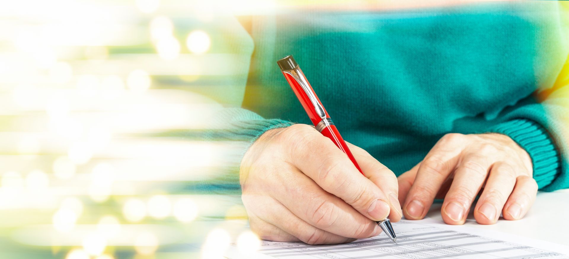 Eine Person schreibt mit einem roten Stift auf ein Blatt Papier.