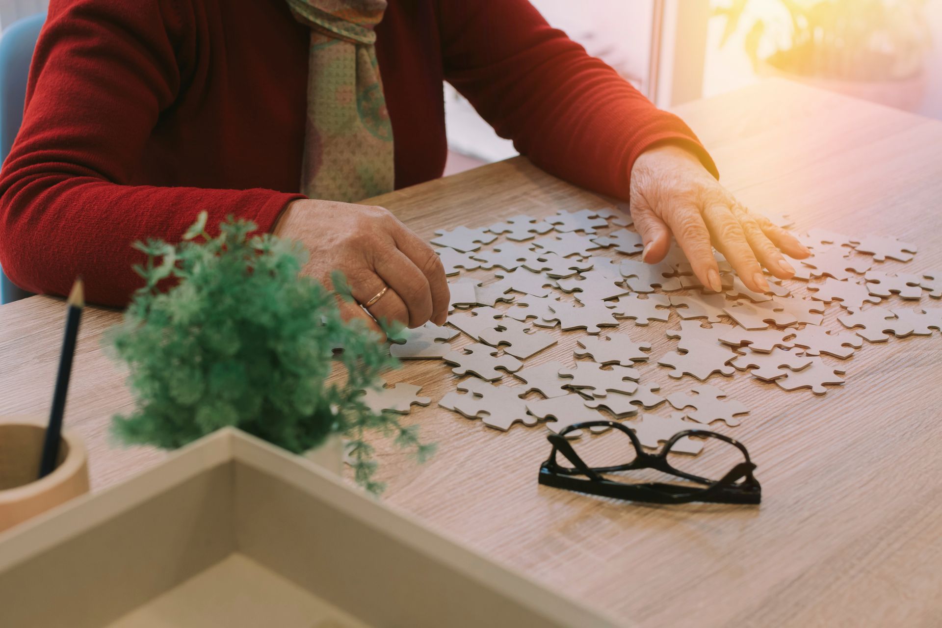Eine ältere Frau sitzt an einem Tisch und spielt ein Puzzle.