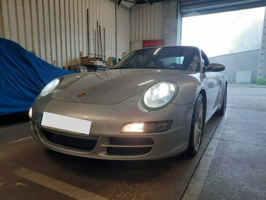 Une voiture grise avec les phares allumés.