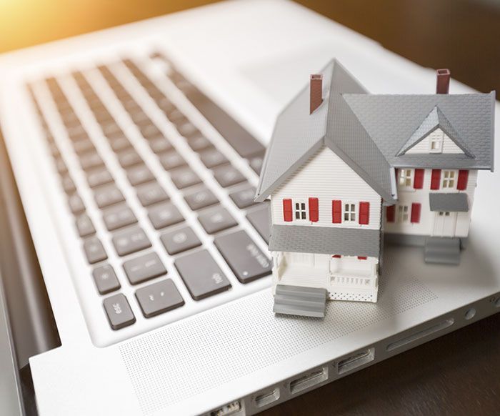 Dos casas pequeñas están sentadas encima de un teclado de computadora portátil.
