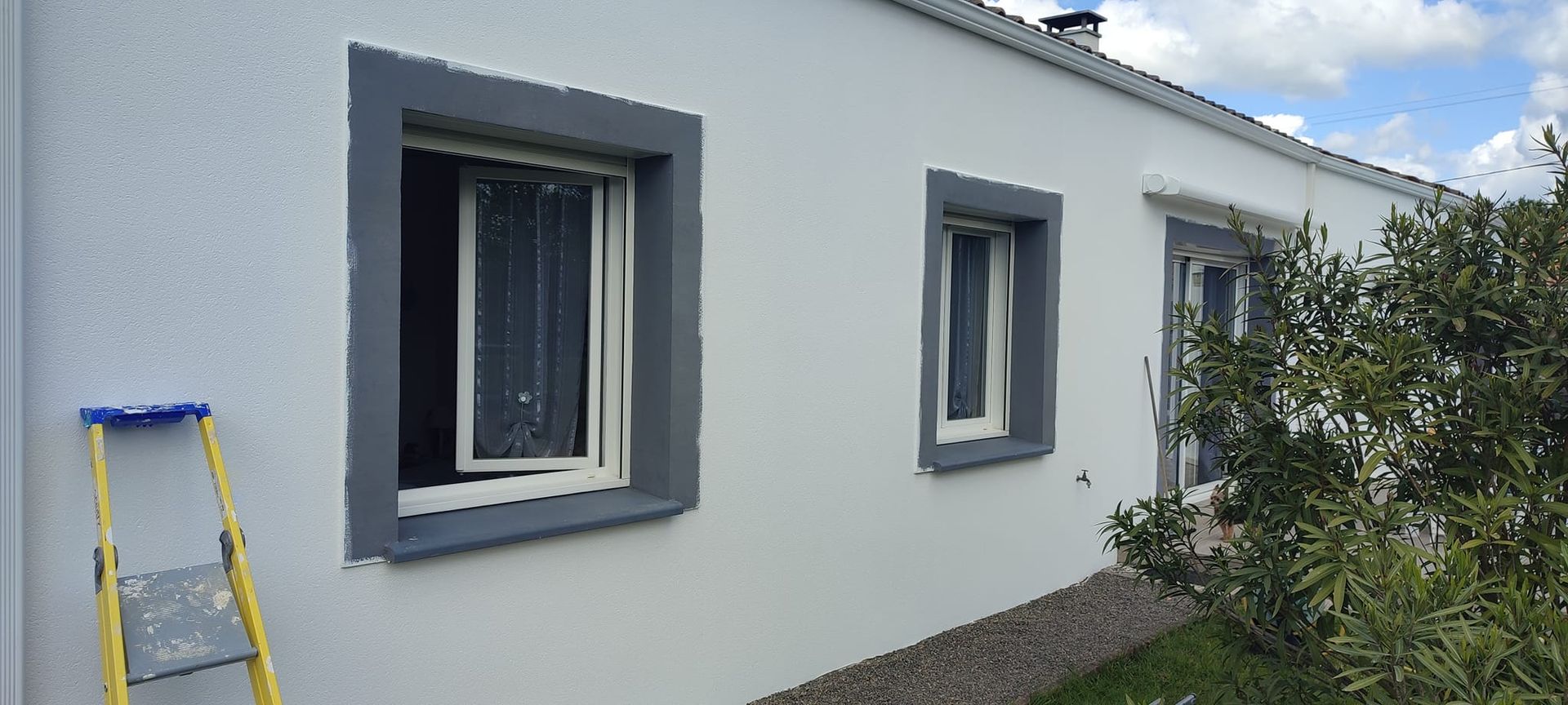 Photo de la façade d'une maison vue de près, avec le contour des ouvertures gris