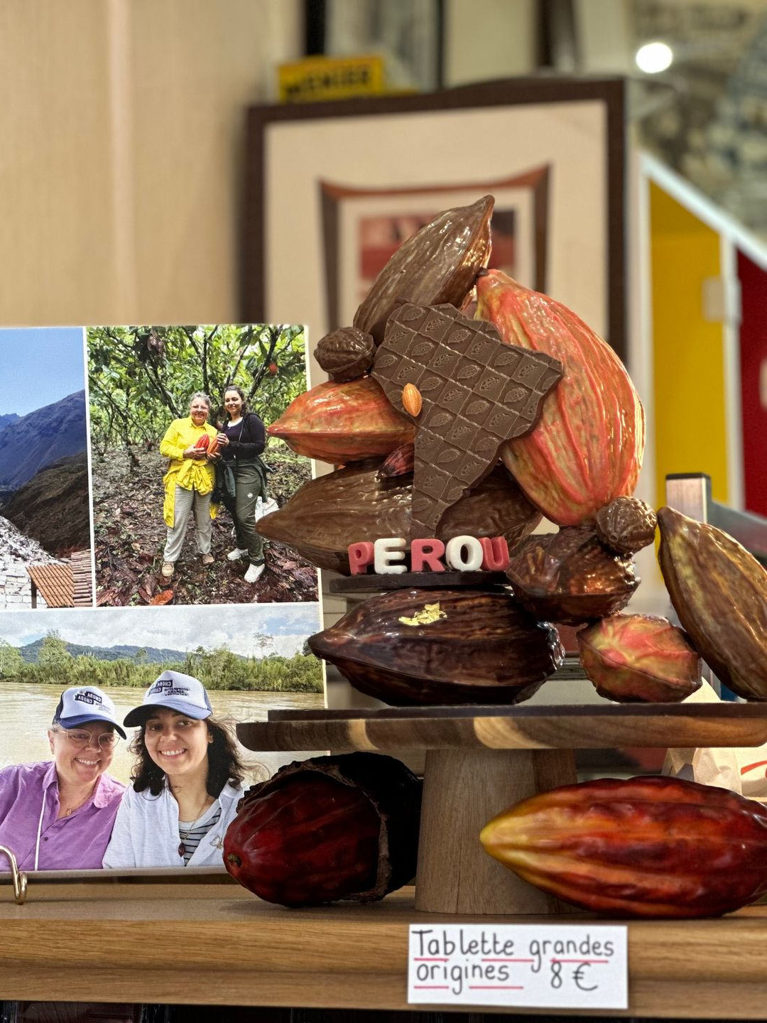 Présentoir de souvenirs du Pérou avec des cabosses de cacao et des petites photos de voyage sur une table, avec une étiquette « Tablette grandes origines ».