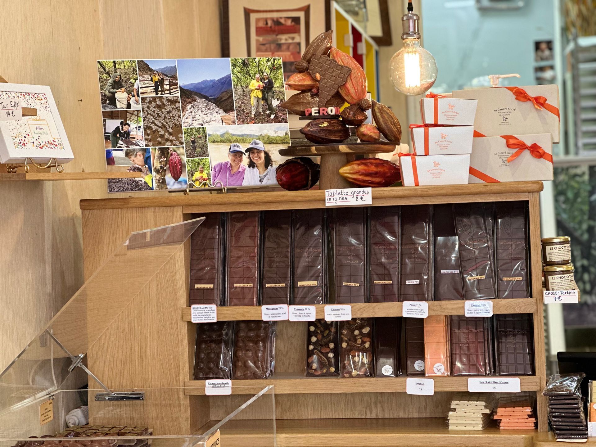 Étagère en bois présentant des produits emballés, des photos et des petites pancartes à l'intérieur d'un magasin
