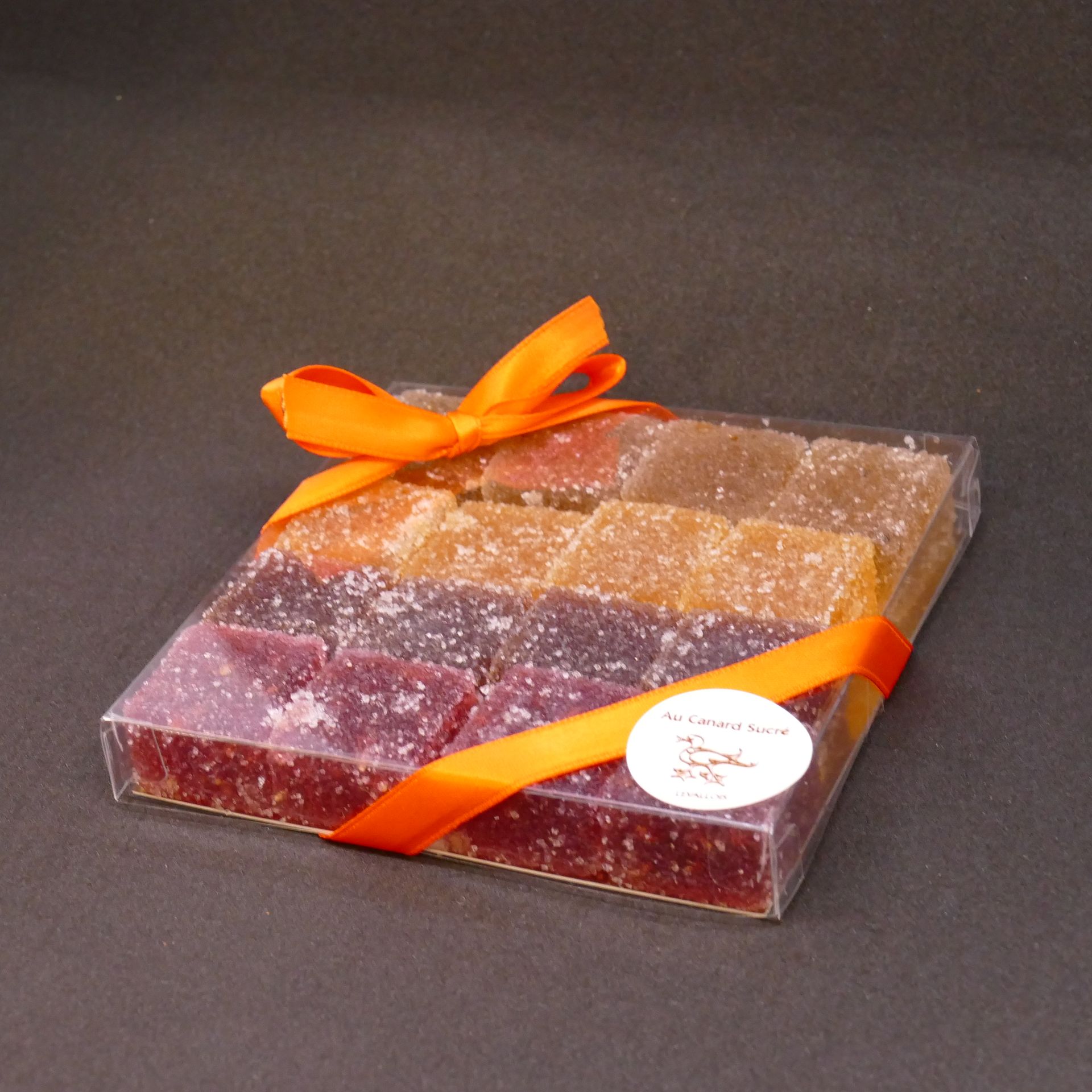 Boîte cadeau emballée avec un ruban orange sur fond sombre