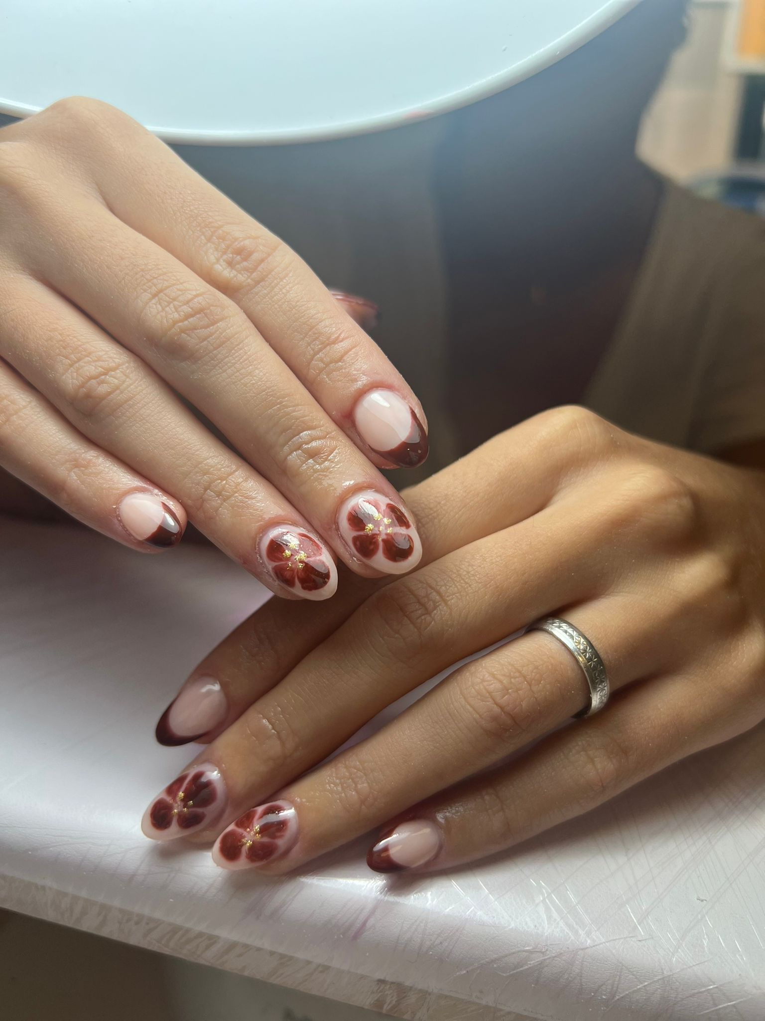 Manos con uñas cuidadas, puntas francesas con rojo oscuro y diseños florales.