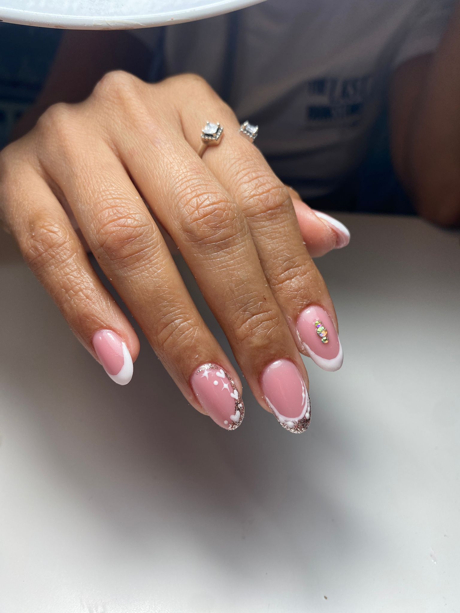 Manicura francesa con puntas blancas sobre uñas de forma ovalada, acentos brillantes.