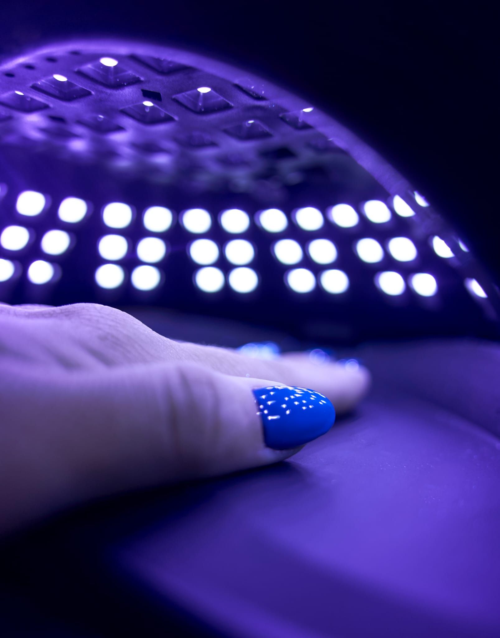 Manos recibiendo una manicura; esmalte de uñas oscuro y blanco.