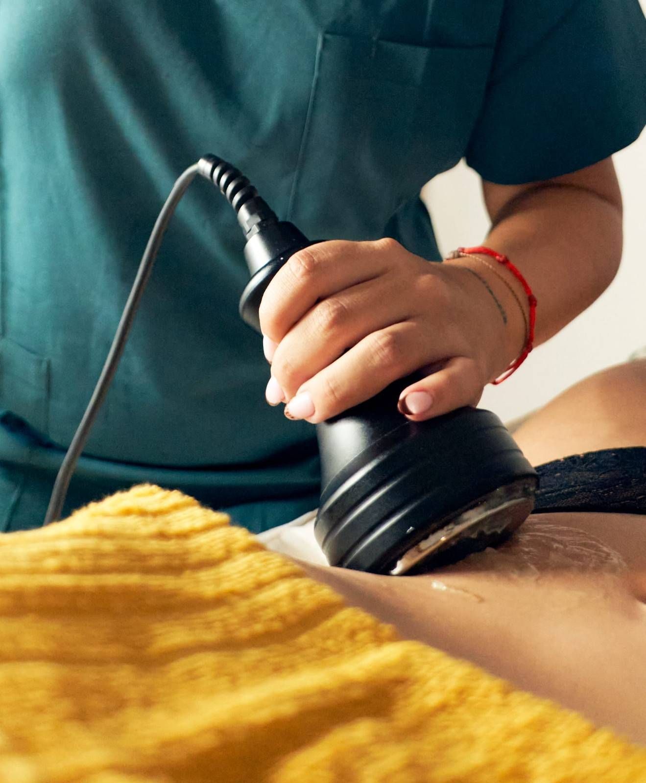 Persona que utiliza un dispositivo de contorno corporal sobre un torso cubierto con una tela amarilla.