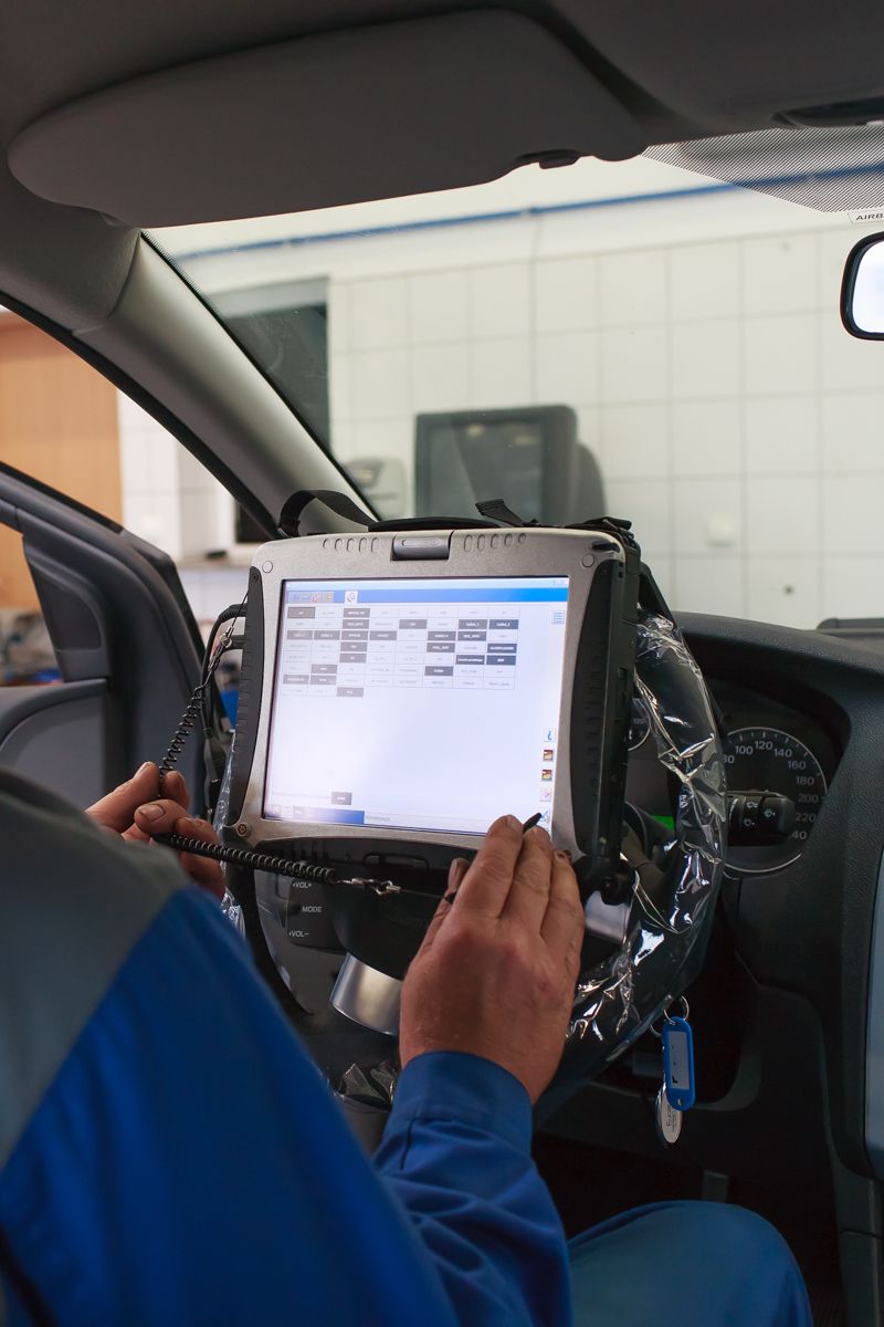 Ein Mann sitzt in einem Auto und nutzt einen Tablet-Computer.
