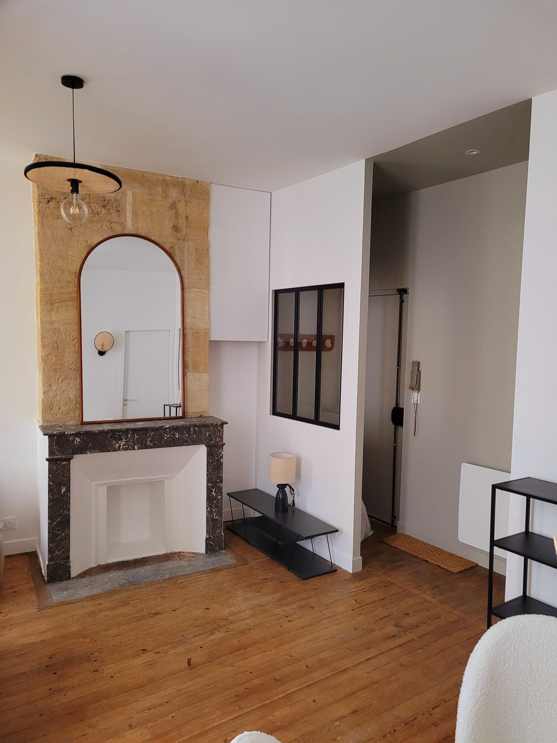 Salon élégant avec miroir arrondi et parquet chaleureux