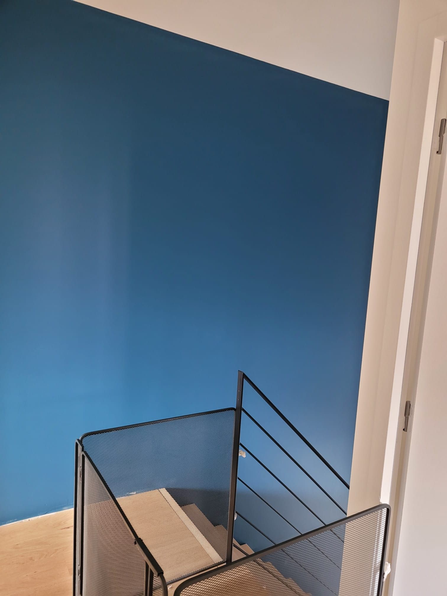 Mur bleu vif avec rampe d’escalier métallique