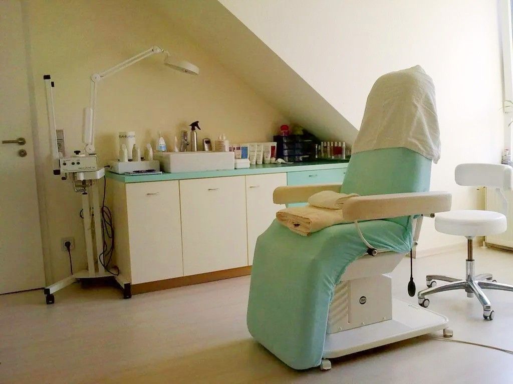 Ein Stuhl mit grünem Bezug steht in einem Raum mit weißen Schränken.