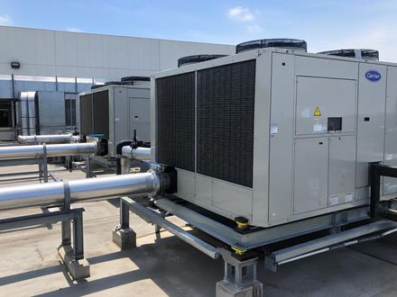 Unidad de aire acondicionado exterior con herramientas y suministros de limpieza en un patio.
