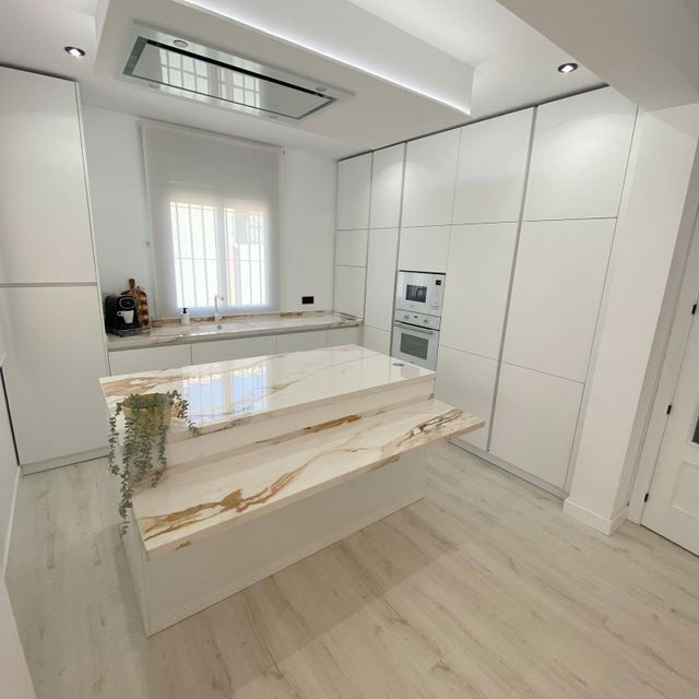 Una cocina con gabinetes blancos y una gran isla en el medio.