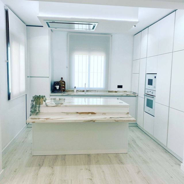 Una cocina con gabinetes blancos y una gran isla en el medio.