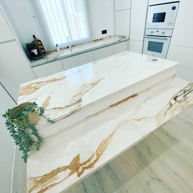 Una cocina con encimera de mármol y gabinetes blancos.