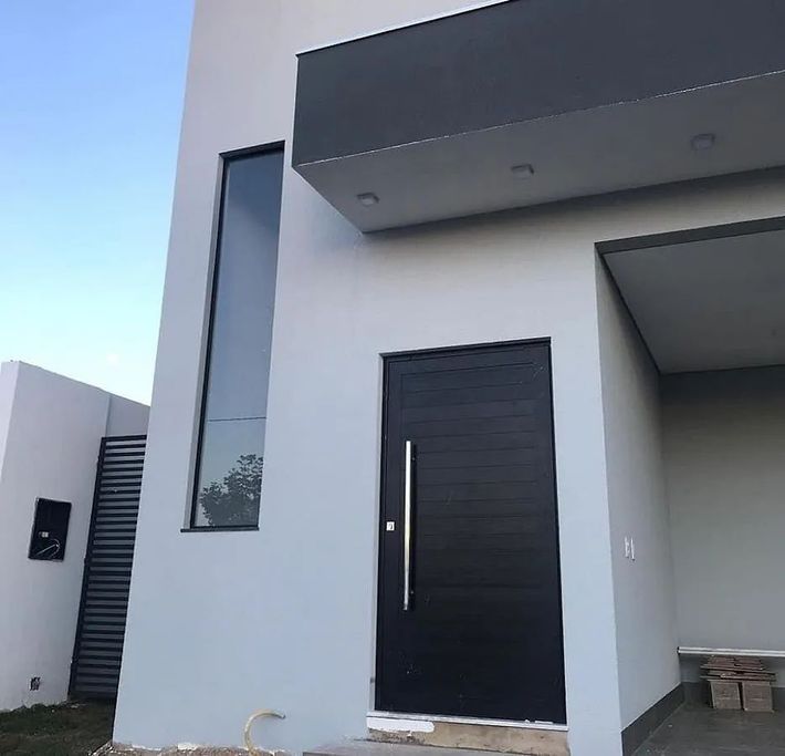Una casa blanca con una puerta negra y una ventana grande