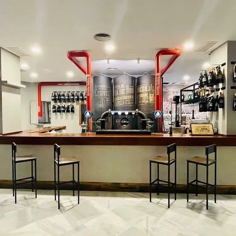 Una barra con taburetes y una pizarra que dice 'cerveza'.