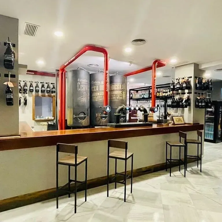 Un bar con taburetes y botellas en la pared.