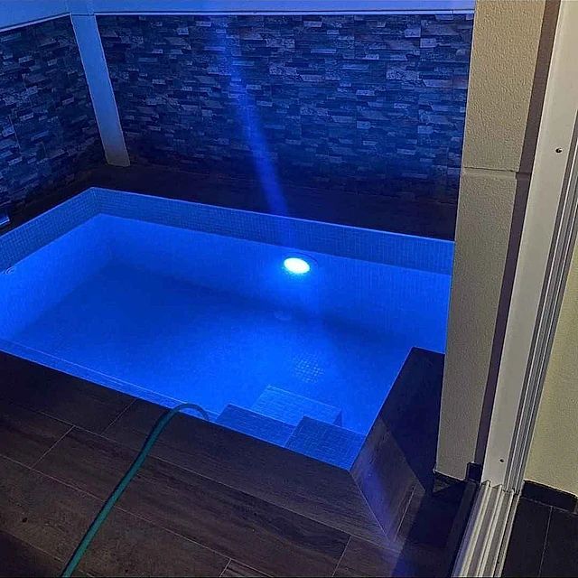 Una piscina está iluminada con una luz azul.