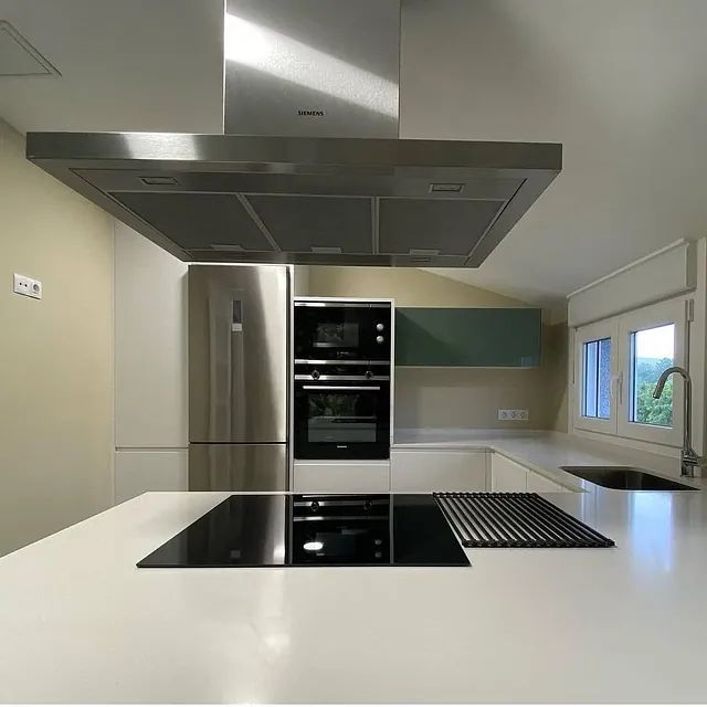 Una cocina con electrodomésticos de acero inoxidable y encimeras blancas.