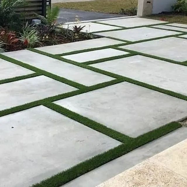 Un camino de entrada de hormigón con césped entre las baldosas.