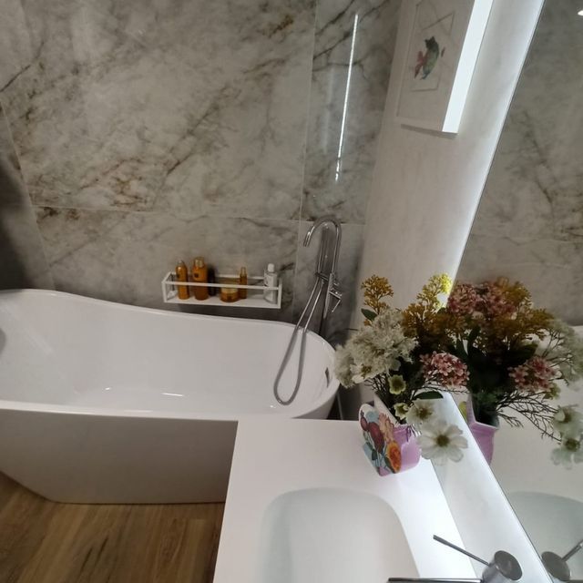 Un baño con bañera, lavabo y espejo.