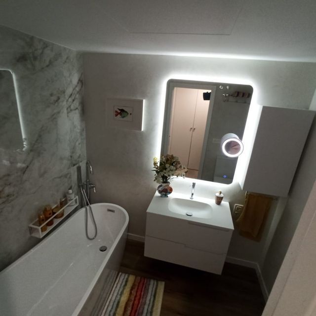 Un baño con bañera, lavabo y espejo.