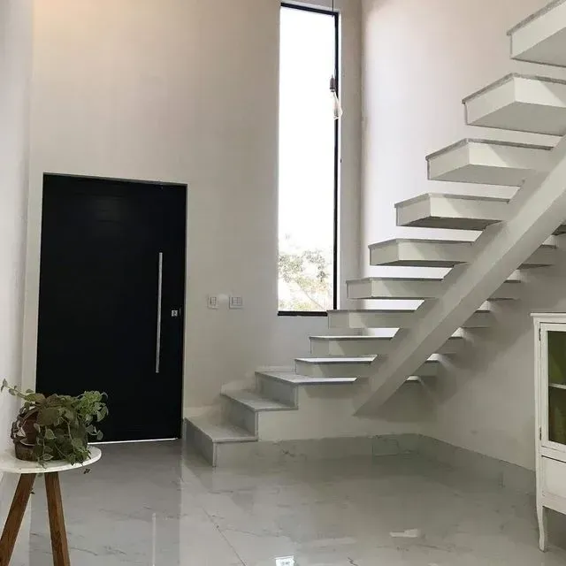 Una escalera blanca en una habitación con una puerta negra.