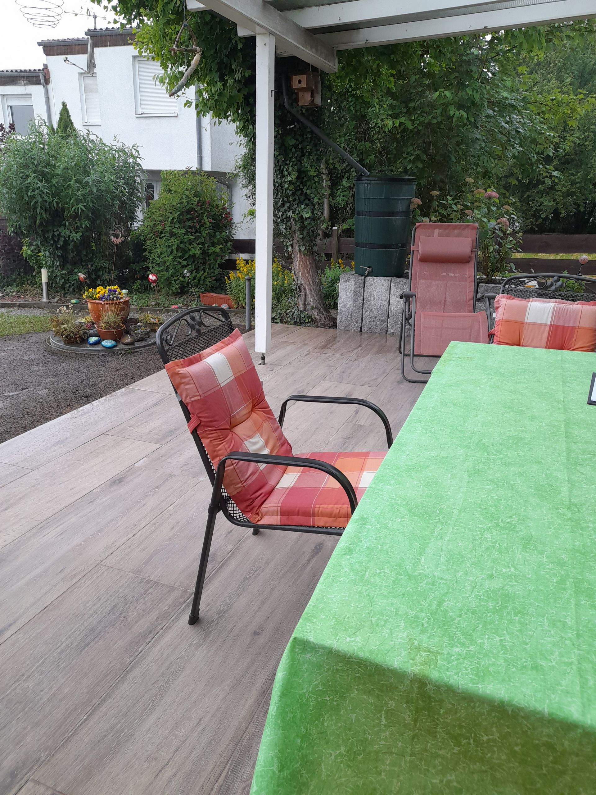Terrasse im Freien mit Stuhl, Tisch und grüner Tischdecke.