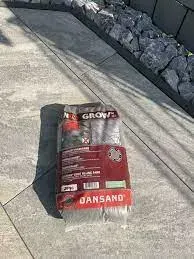 Auf einem Gehweg neben einer Felswand steht ein Sack Sand.