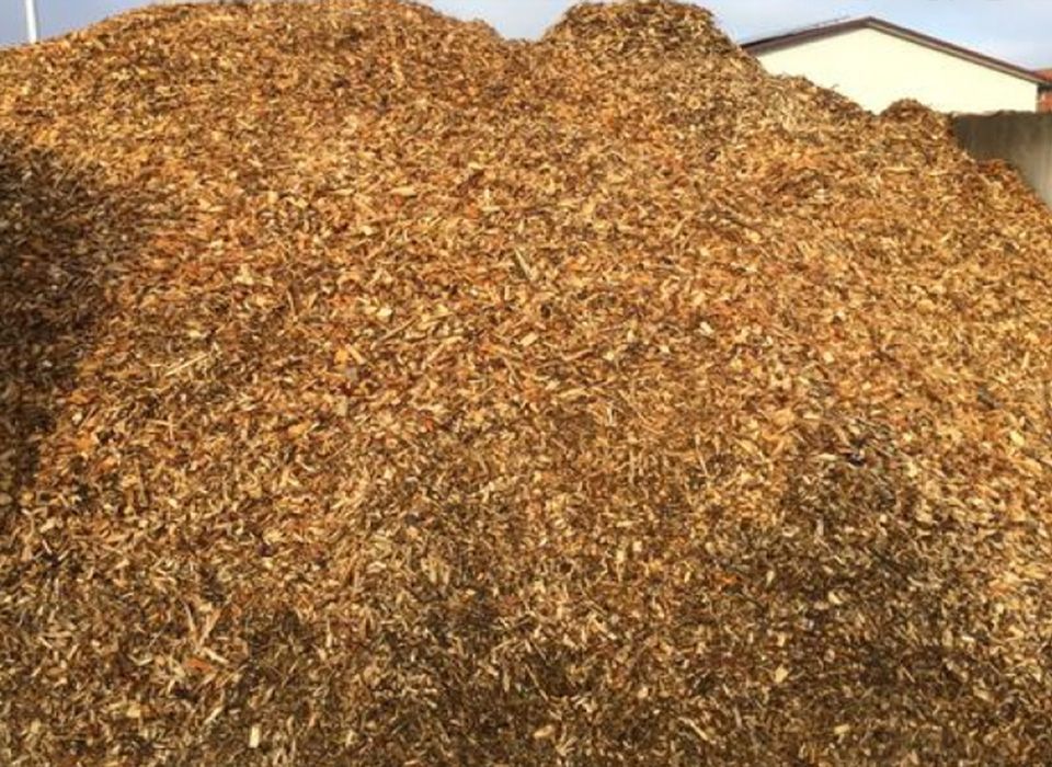 Vor einem Gebäude liegt ein Haufen Holzspäne.