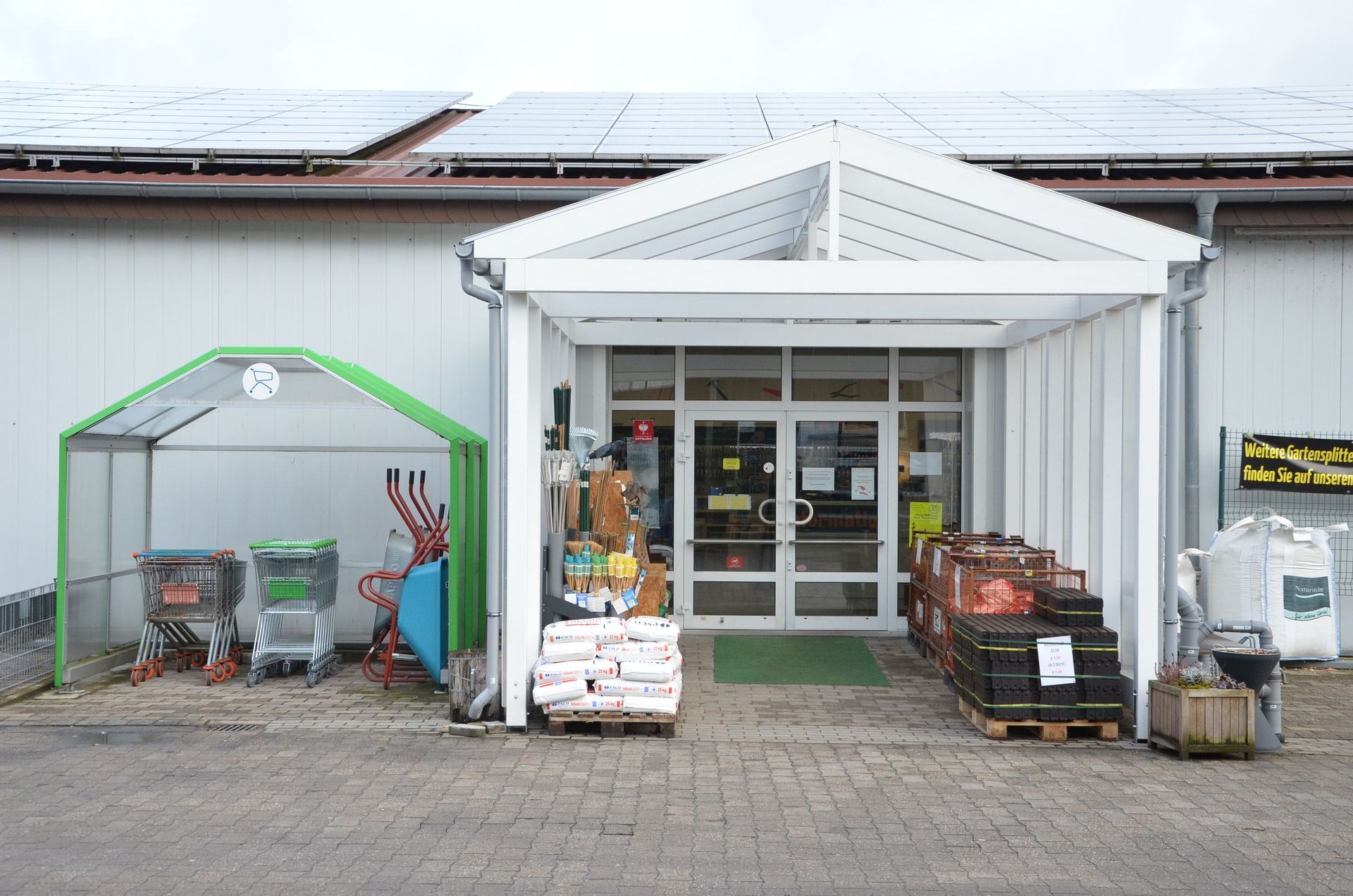 Eine Ladenfront mit einem Gewächshaus davor.