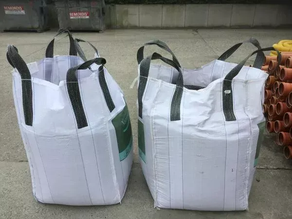 Zwei weiße Taschen mit schwarzen Griffen liegen nebeneinander auf dem Boden.