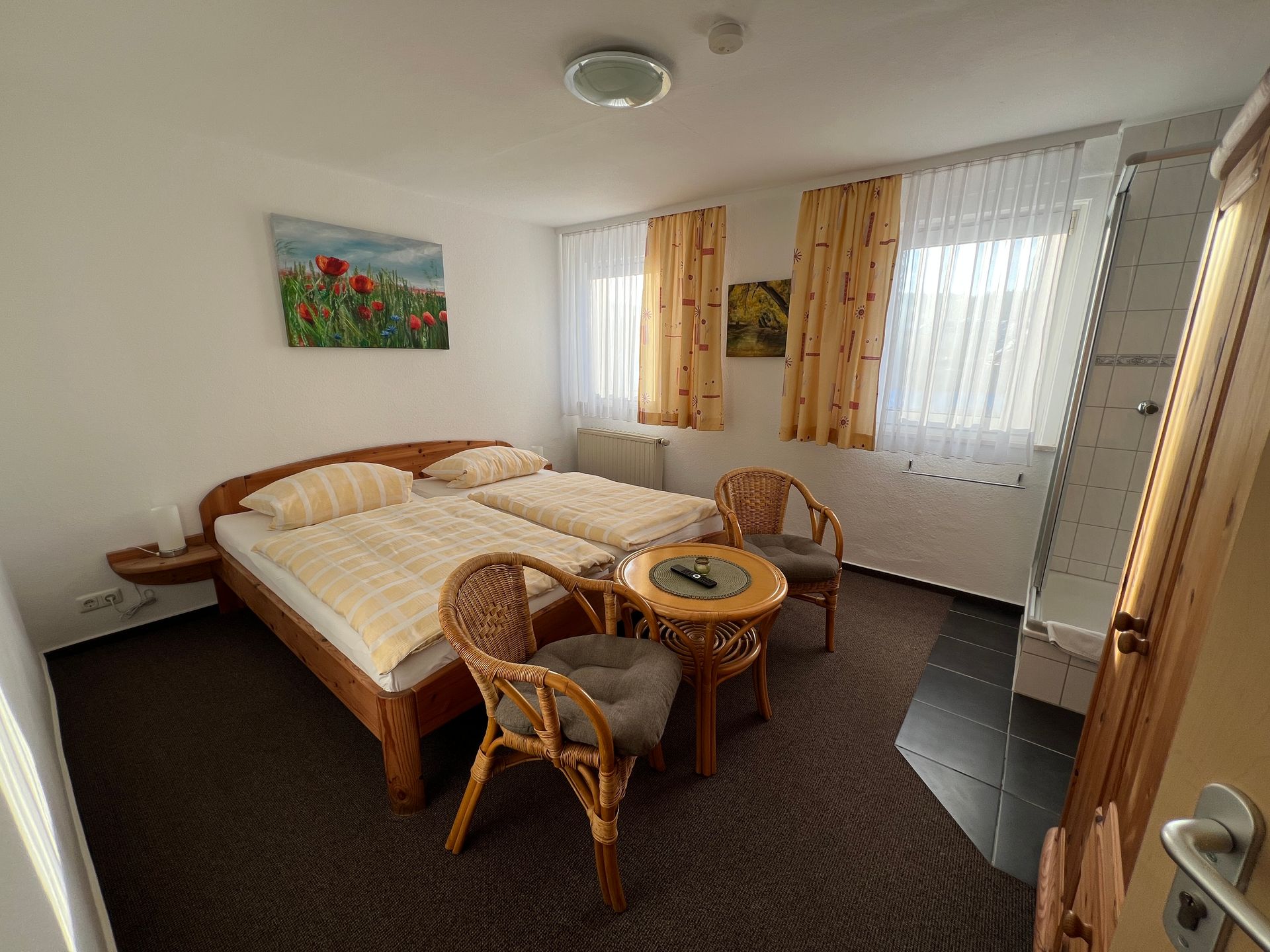 Hotelzimmer mit Kleiderschrank, Dusche, Waschbecken, Tisch, Stühlen und Fenster.