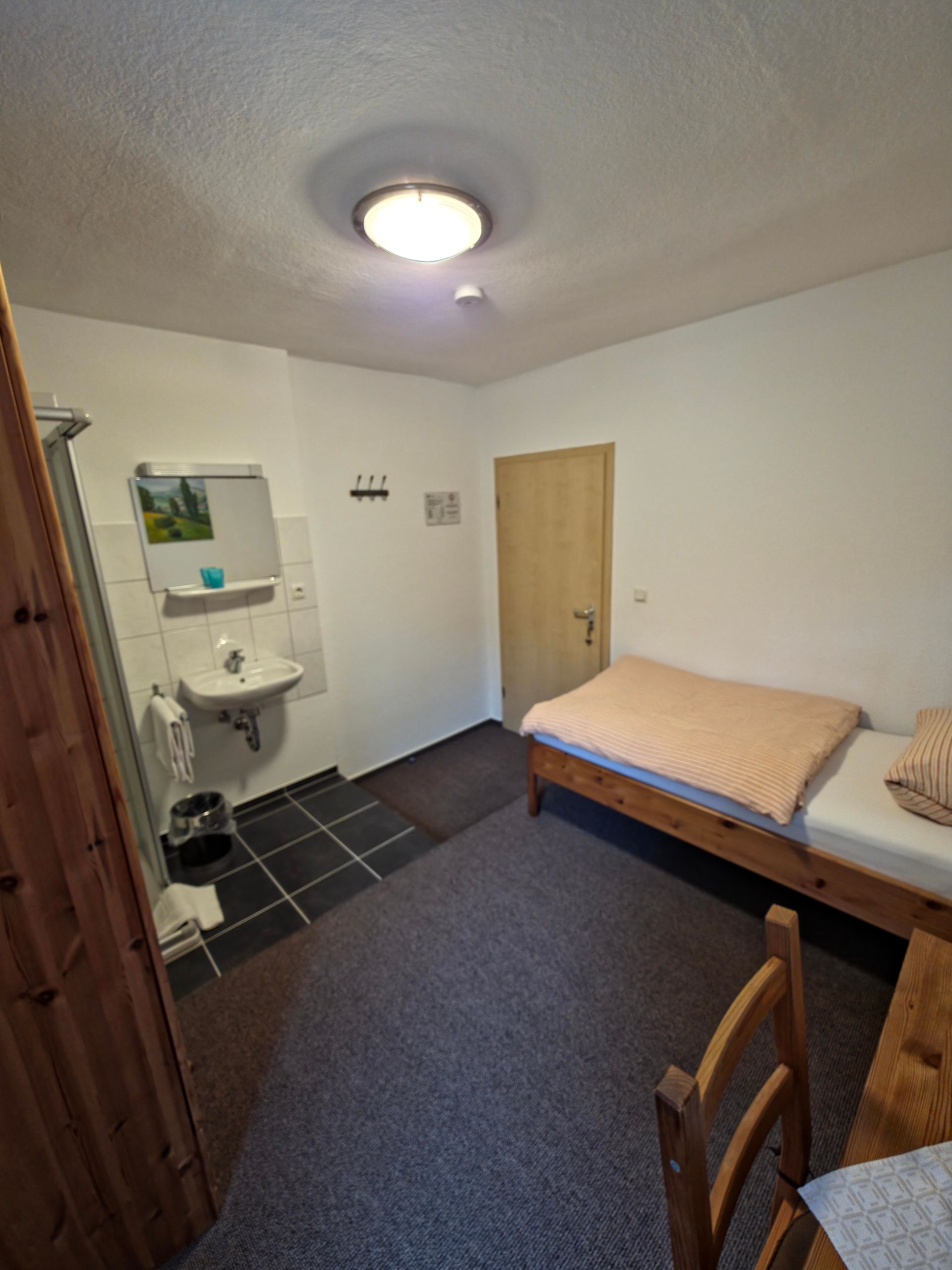 Ein Hotelzimmer mit Doppelbett, Korbsesseln und einem kleinen Tisch am Fenster.