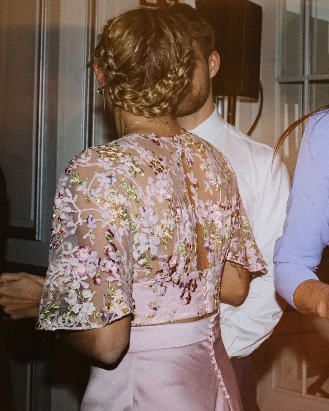 Una mujer con un vestido rosa está de pie junto a un hombre con una camisa blanca.