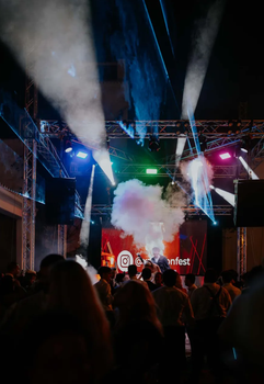 Escenario de conciertos con luces y humo, sobre la multitud. Una pantalla muestra 