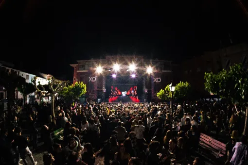 Concierto de noche: gran multitud frente a un escenario iluminado con "XO" en luces.